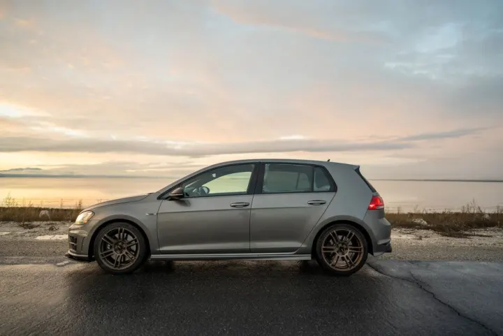 Silver VW Golf on a coastal road at sunrise